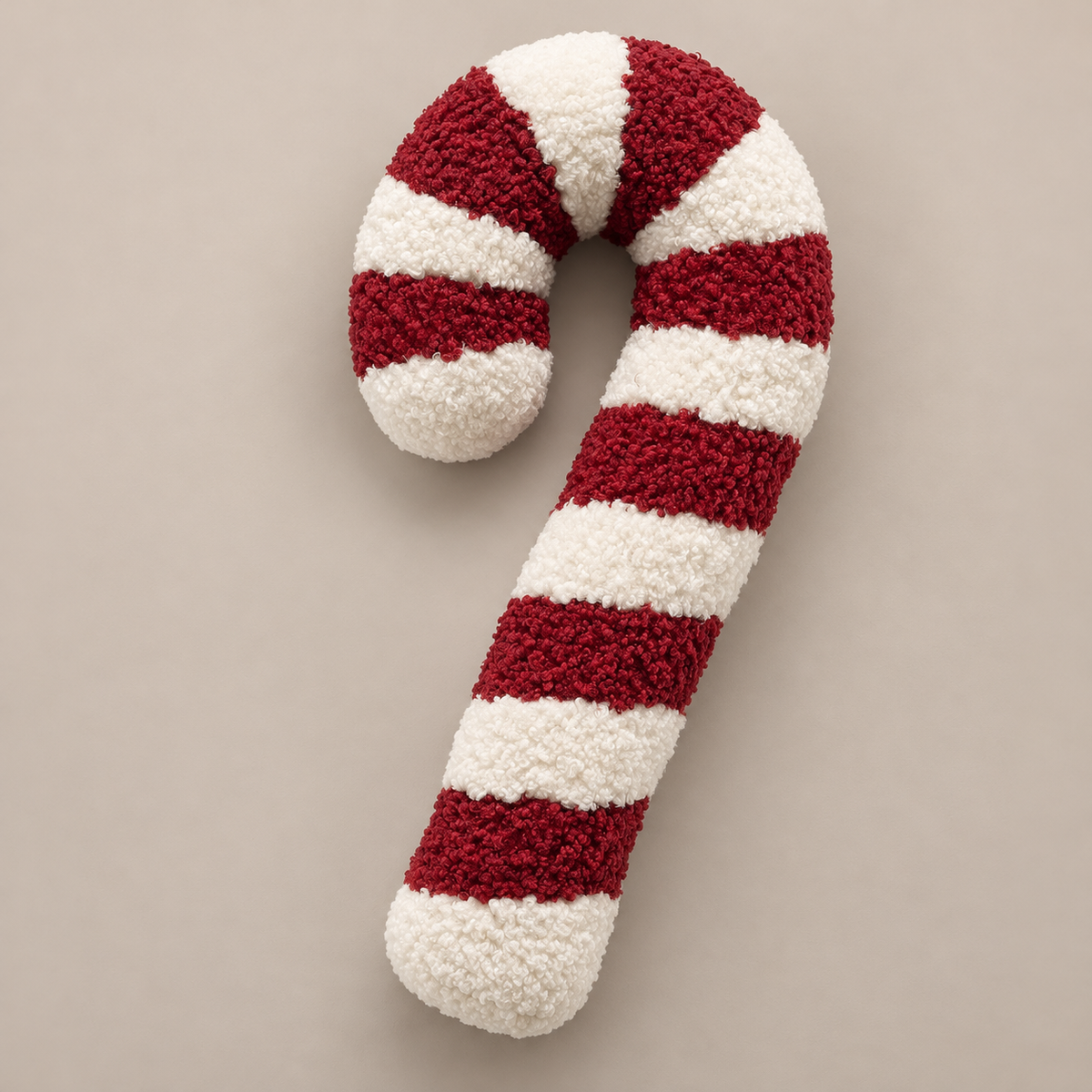 Zuckerstangen-Kissen Candy Cane seitlich auf einer taupefarbenen Fläche.