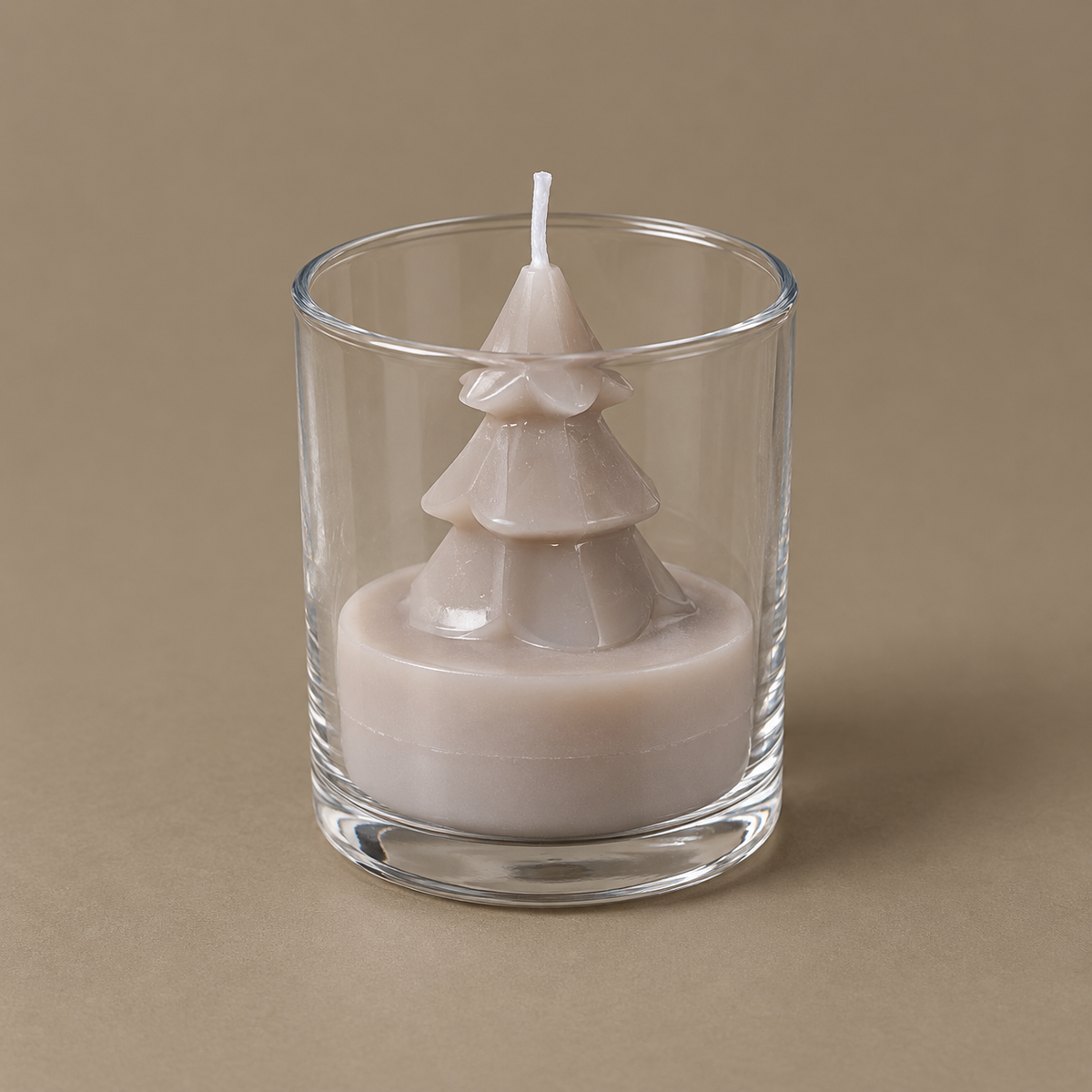 Taupefarbene Tannenkerze Tree Candle im klaren Glas freigestellt aus erhöhter Perspektive vor ruhigem Naturton