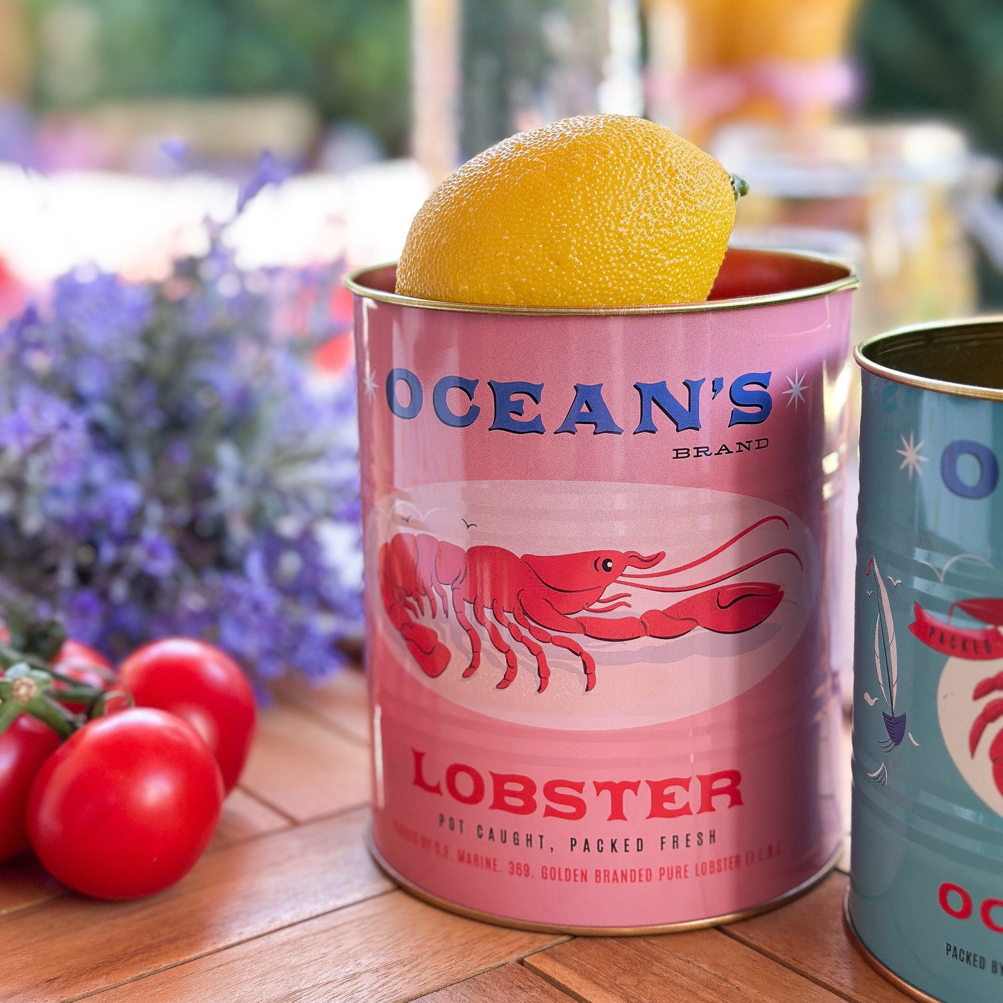 Zwei dekorative Metall-Aufbewahrungsdosen "Ocean's Brand" von Rex London, mit maritimen Design, auf einem Tisch.