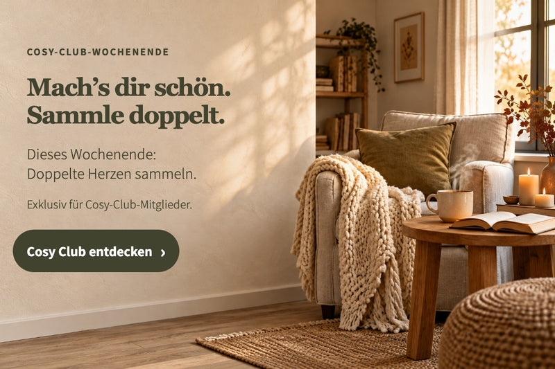 Doppelte Herzen sammeln am Cosy-Club-Wochenende. Gemütliche Leseecke mit Strickdecke, Tasse und Kerzen; Cosy Club entdecken.
