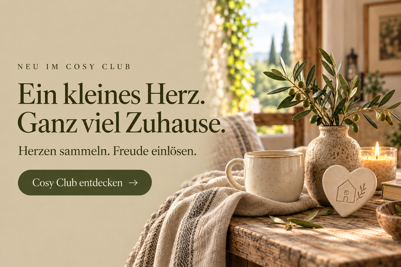 Ein kleines Herz, ganz viel Zuhause: Cosy Club mit einer warmen Wohnszene und dem Hinweis auf das Herzensammeln.