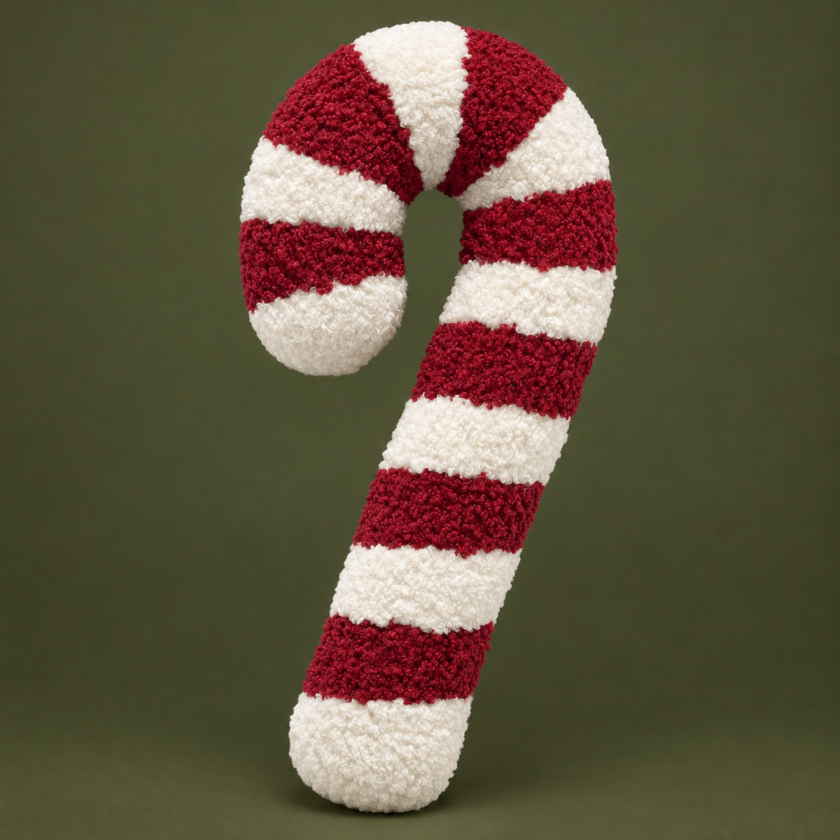 Dekokissen Candy Cane in Rot und Weiß mit Bouclé-Struktur vor olivfarbenem Hintergrund.