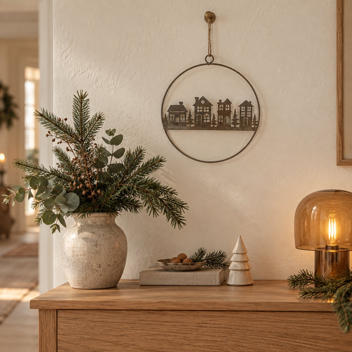 Metallring Vinterby mit Dorfmotiv über einem Holzsideboard mit Winterzweigen