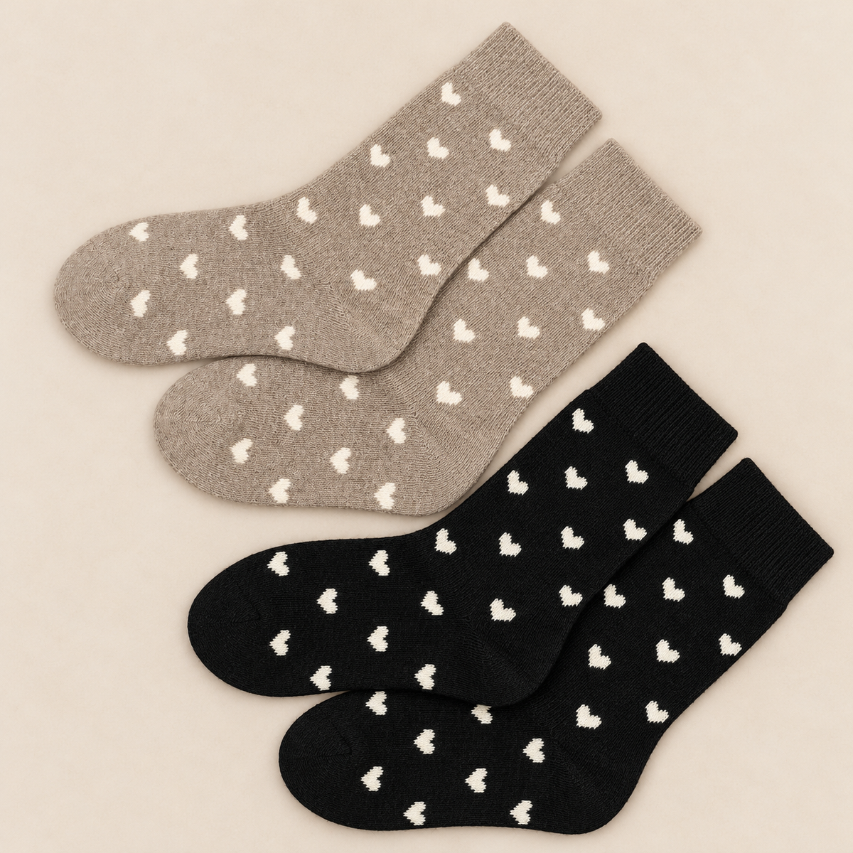 Zwei Paar Herzsocken in Taupe/Schwarz auf hellem Naturhintergrund