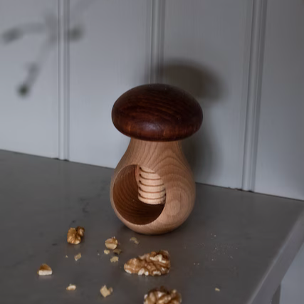 Nussknacker Pilz aus Holz mit Walnüssen auf einer Küchenfläche
