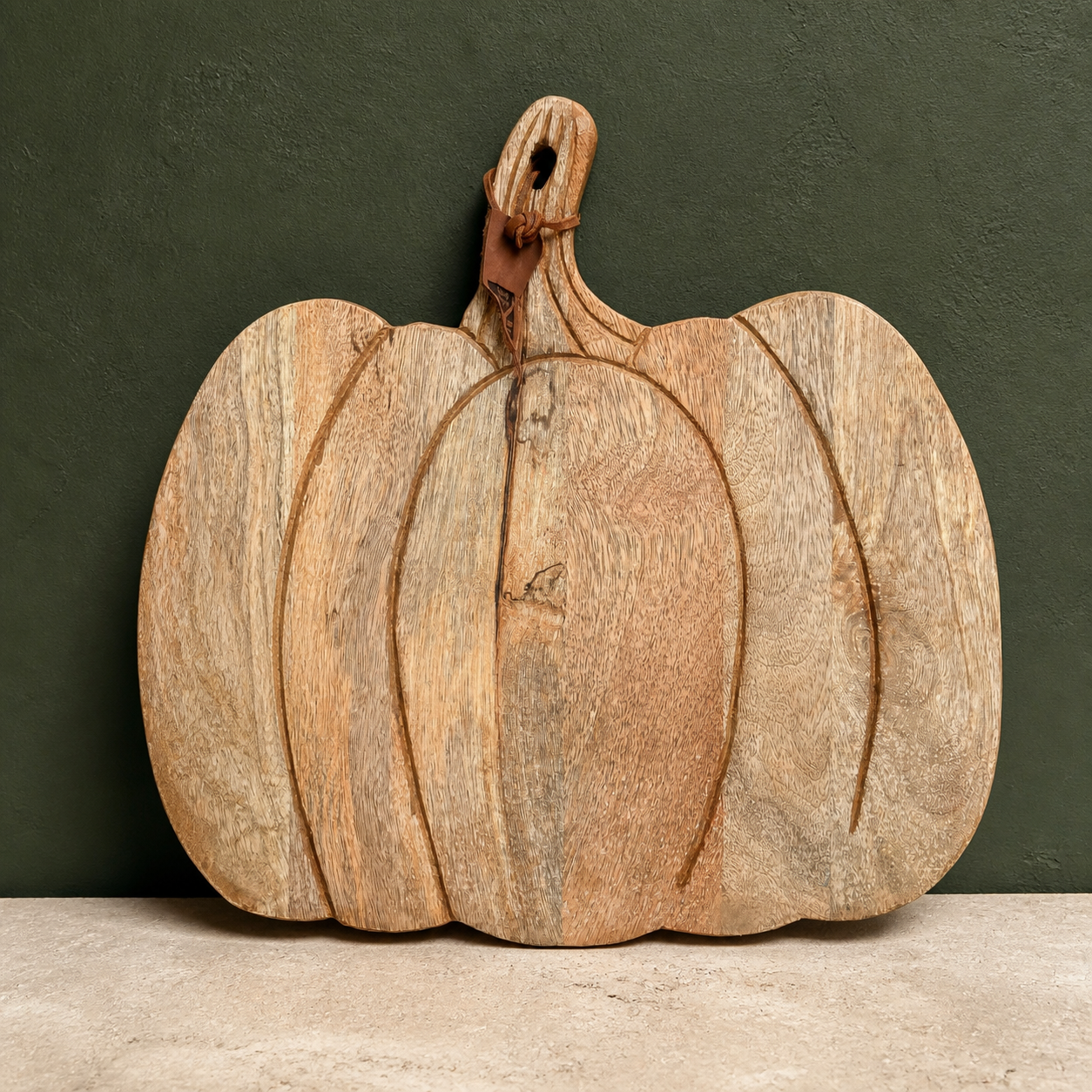 Kürbisförmiges Mangoholz-Brett "Pumpkin" vor dunkelgrünem Hintergrund