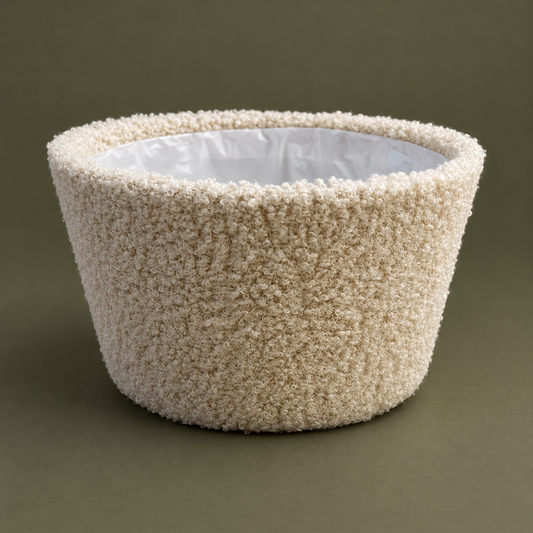 Cremefarbene Teddy-Schale mit feiner Schlingenstruktur vor dunkelolivfarbenem Hintergrund.