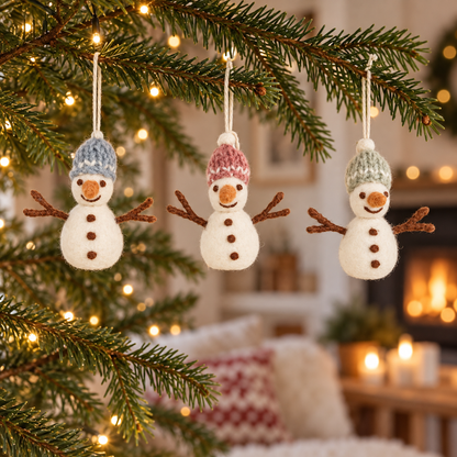 Drei Filz-Schneemänner Schneefreunde mit blauen, rosa und grünen Mützen an einem weihnachtlichen Tannenzweig.