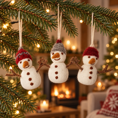 Drei Filz-Schneemänner Winterfreunde mit roten und grauen Mützen an einem weihnachtlichen Tannenzweig.