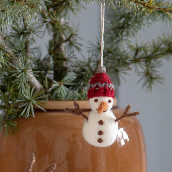 Filz-Schneemann Winterfreunde mit roter Strickmütze am Tannenzweig – Herstelleraufnahme.