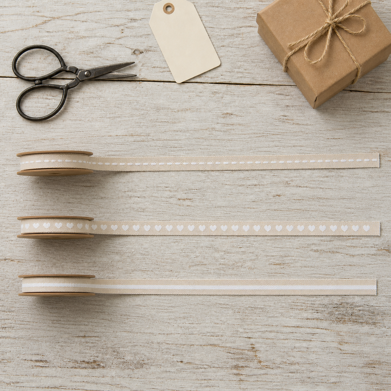 Drei cremefarbene 10-mm-Dekobänder mit weißen Linien und Herzen im Flatlay