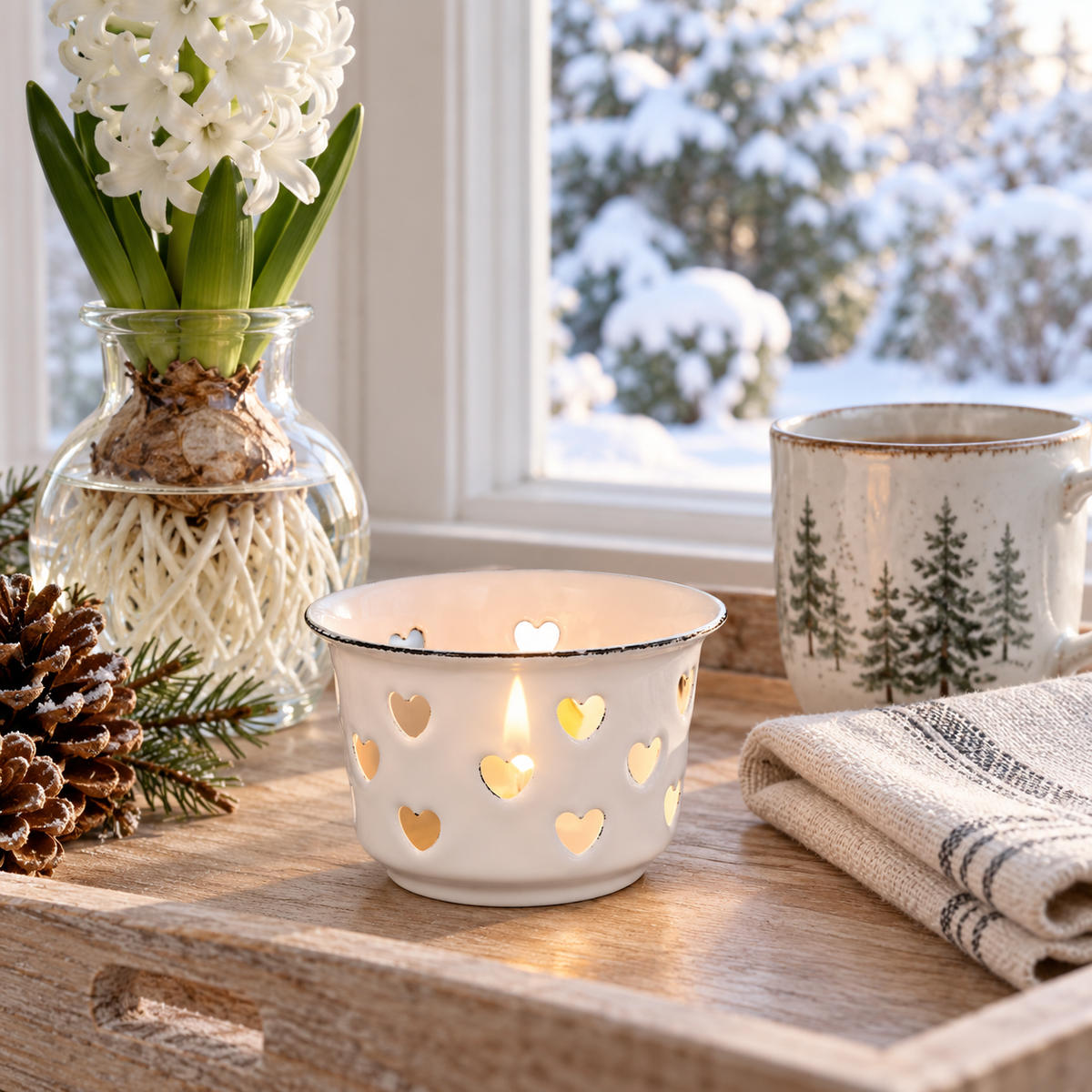 Weißer Emaille-Teelichthalter Candle Kiss mit Herzausschnitten in einer gemütlichen Dekoration am Winterfenster