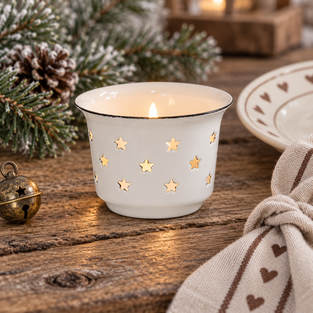 Weißer Emaille-Teelichthalter Nordic Star mit Sternausschnitten im Detail auf einem winterlich dekorierten Holztisch