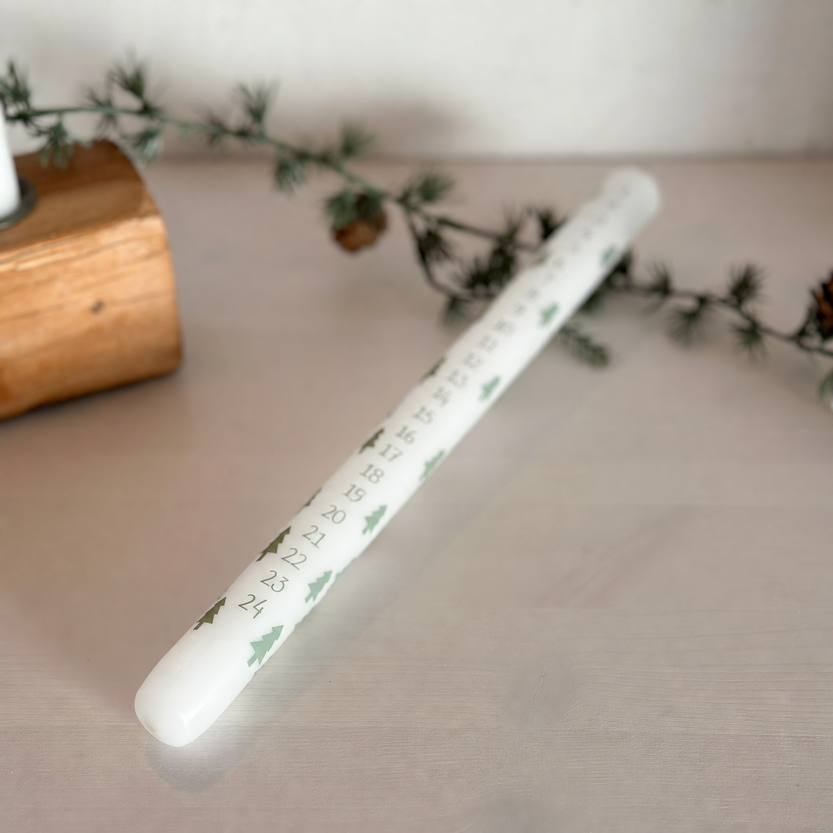 Detail der weißen Adventskerze Weihnachtswald mit grünen Tannenbäumen und Zahlen bis 24