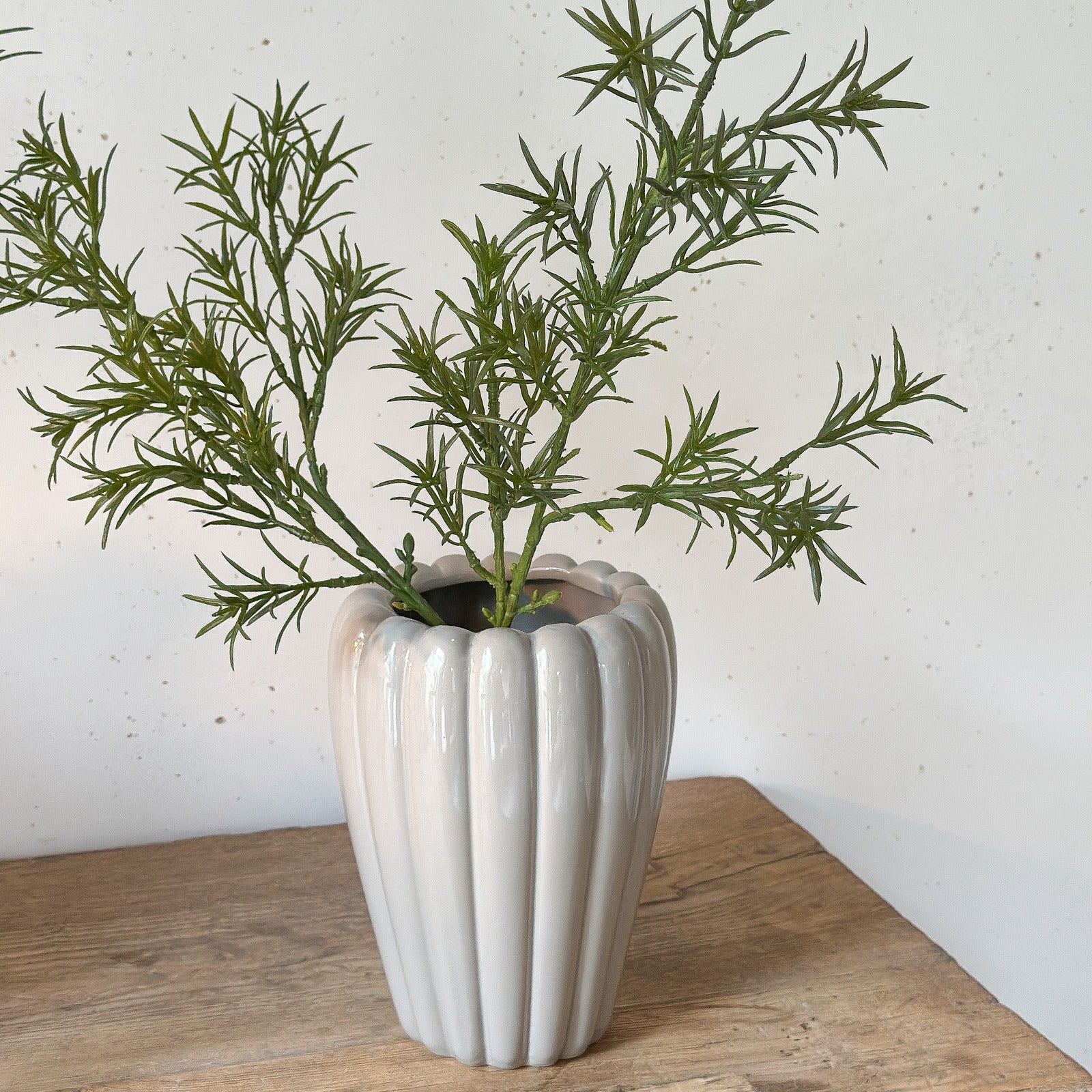 Künstlicher Asparagus-Zweig in Vase dekoriert